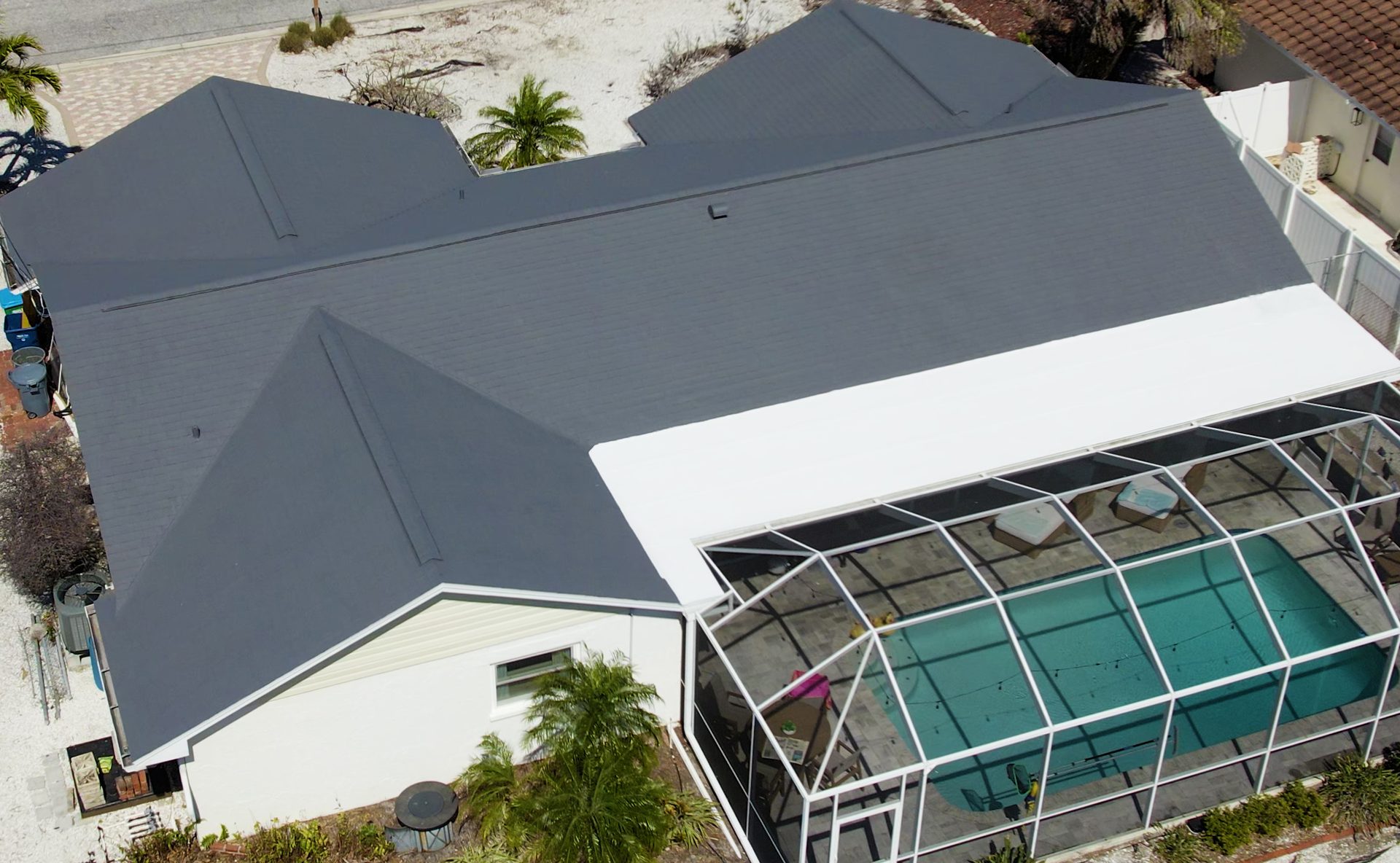 Aerial view of a gray shingle roof beside a screened pool
