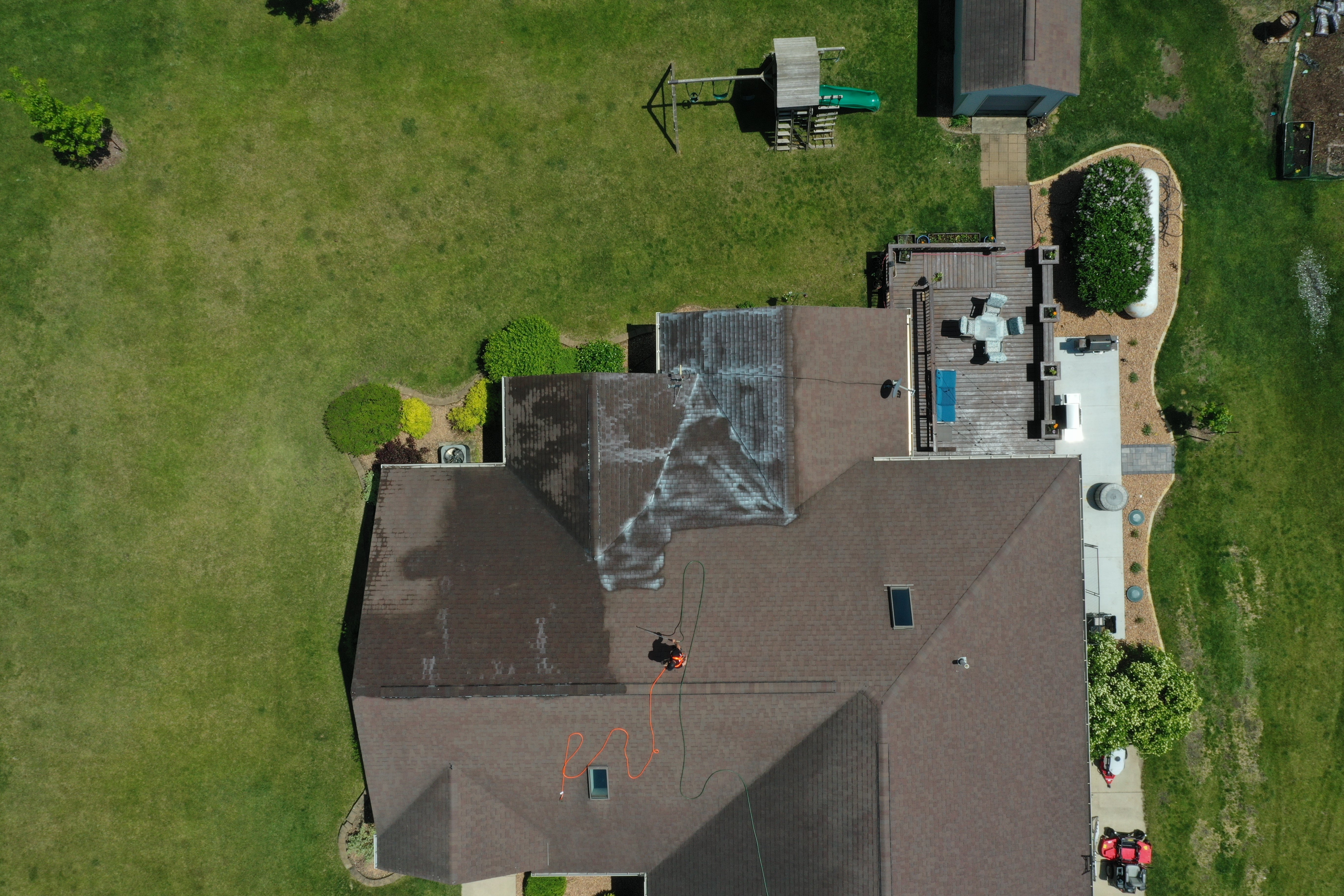 Aerial view of a shingle roof treatment in progress