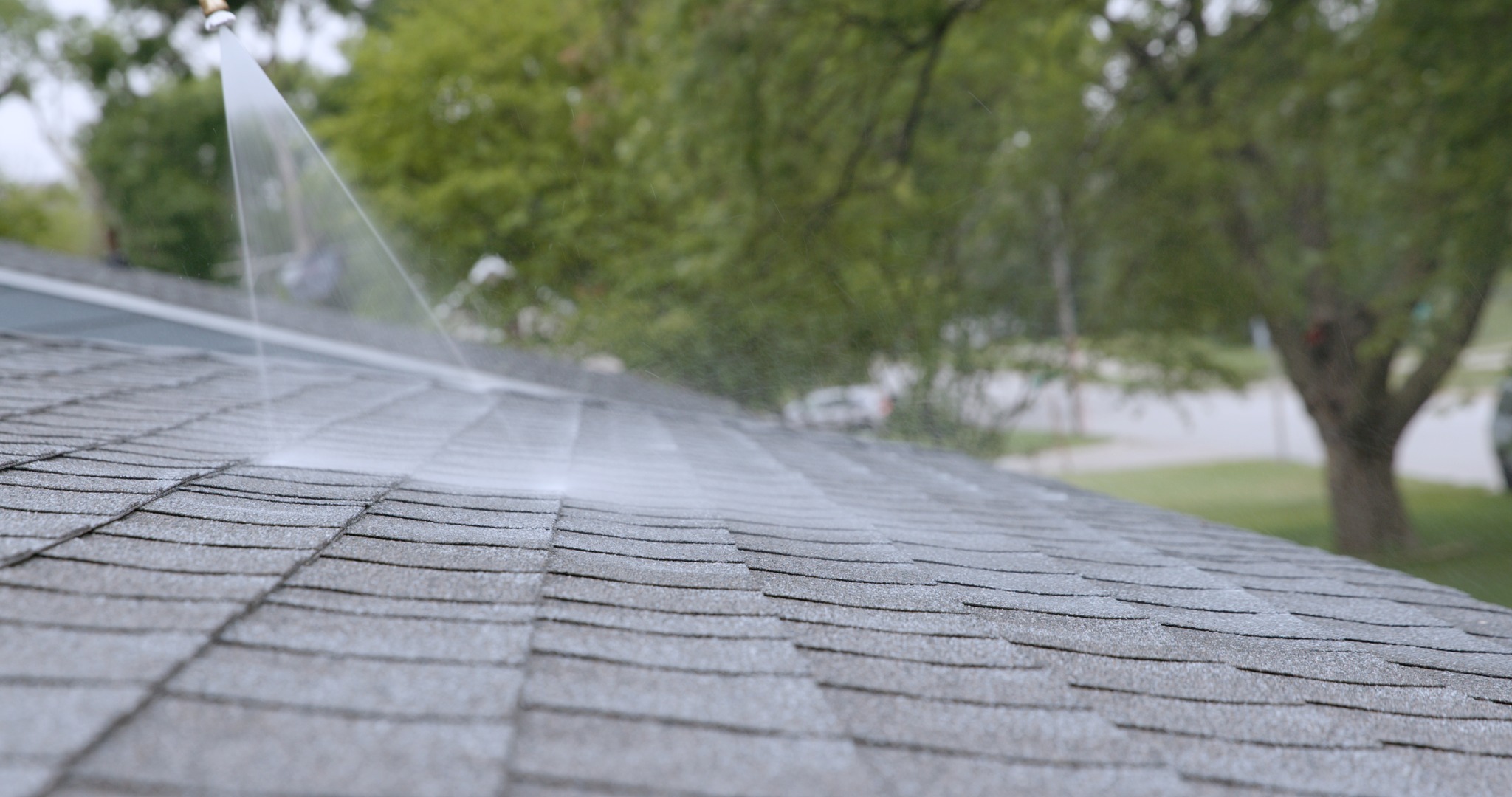 Close-up of Peak 301 treatment being sprayed across asphalt shingles