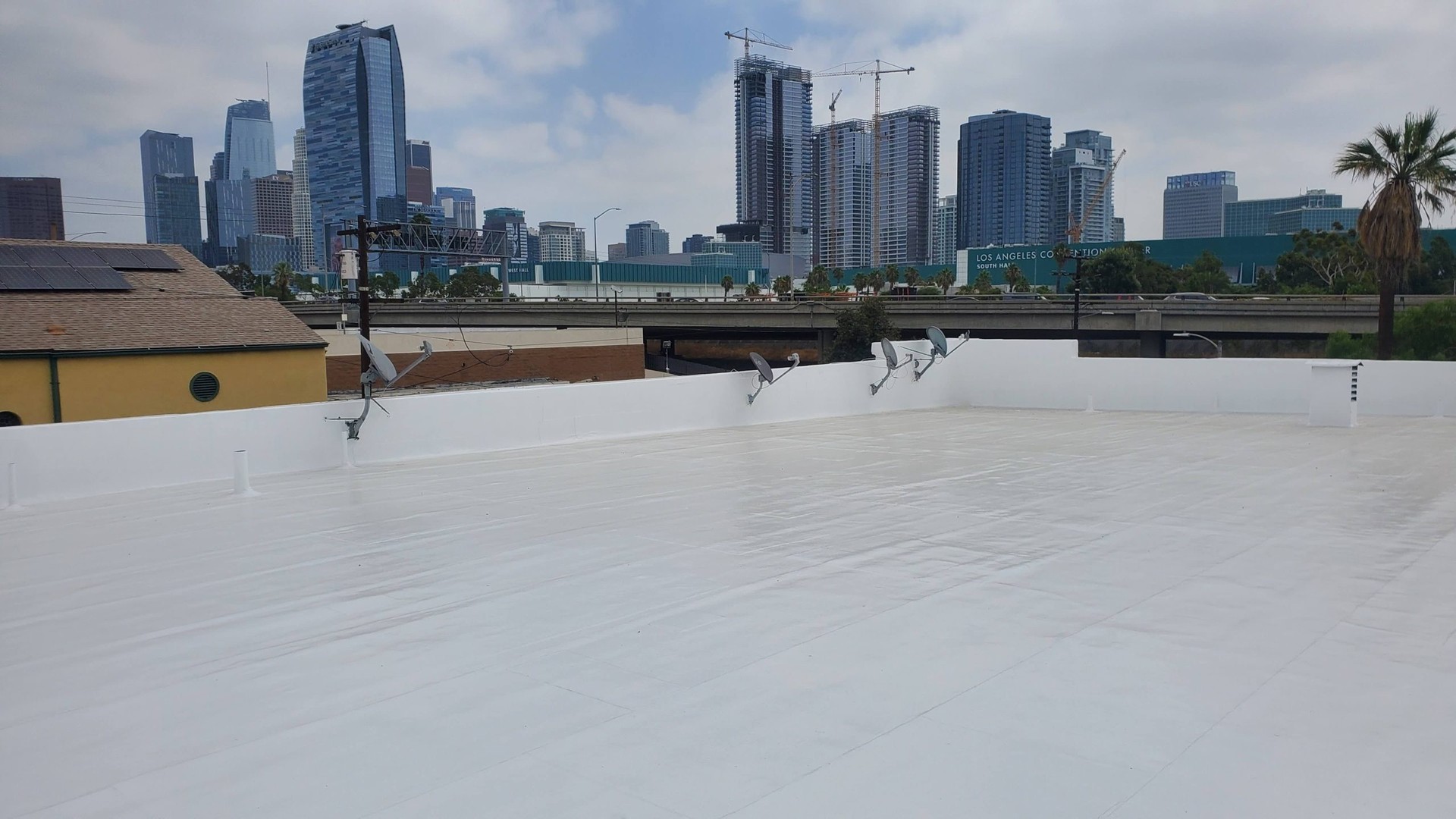 White silicone roof coating being applied to flat commercial roof